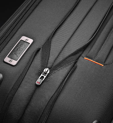 Close-up of a black suitcase with a visible brand logo on a dark background