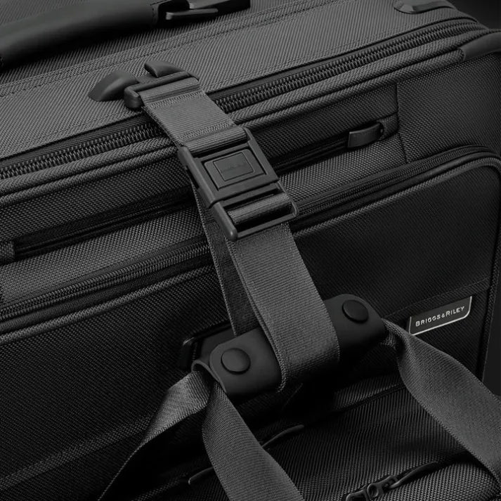 Adjustable strap securing extra bag to large black suitcase